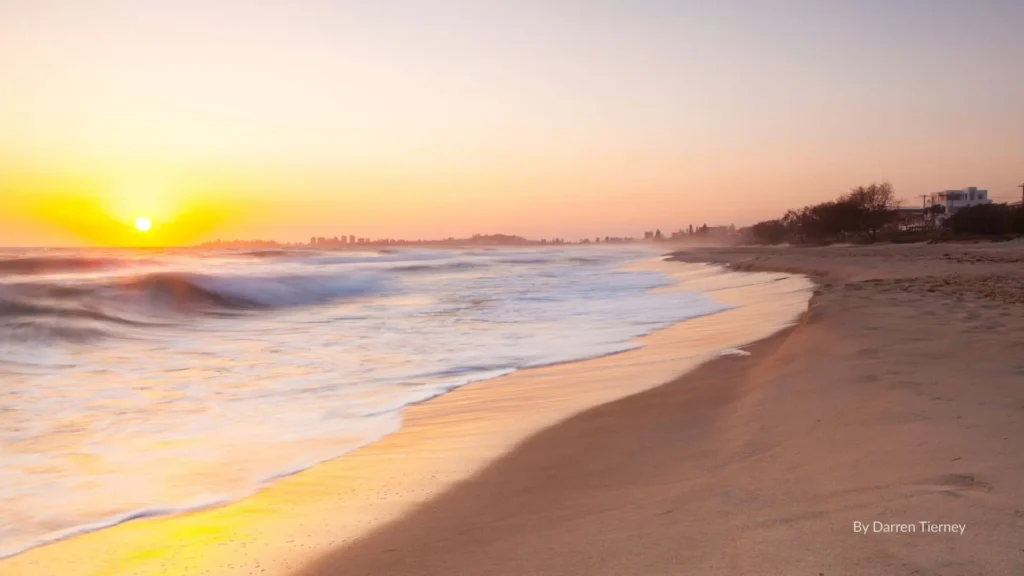 Bilinga Beach at sunrise, golden sandy shoreline with gentle waves and views towards Coolangatta on the Gold Coast