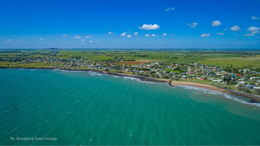 Aerial view of Burnett Heads, Bundaberg Queensland, showing rocky coastline, small sandy stretches, and residential township by the Burnett River mouth