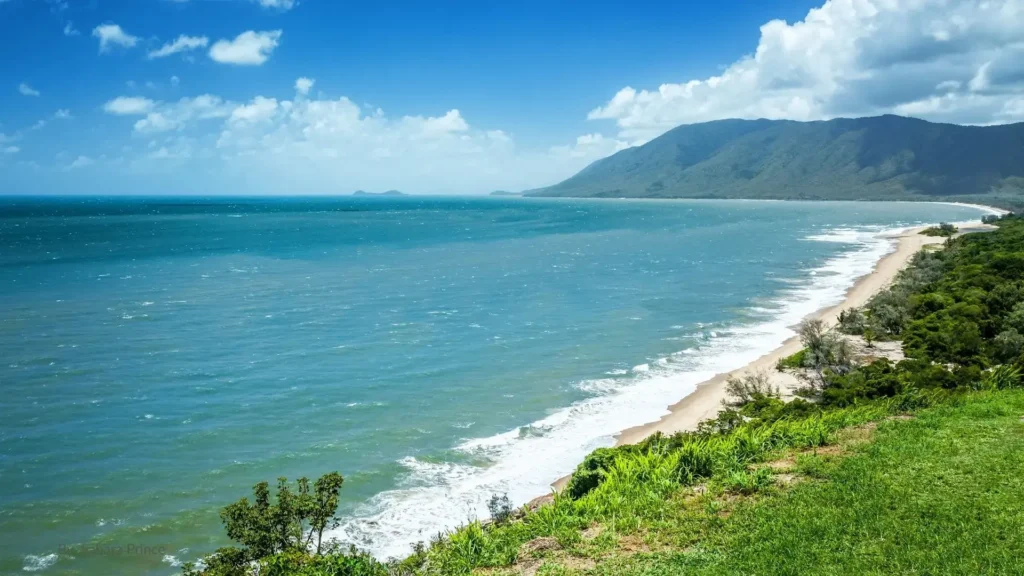 Scenic coastline of Cairns Region with turquoise waters, sandy beach, and mountain backdrop in Tropical North Queensland