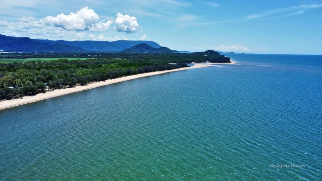 Aerial view of Holloways Beach, Cairns — a relaxed tropical beach with calm waters, shady esplanade, and views of the Coral Sea.