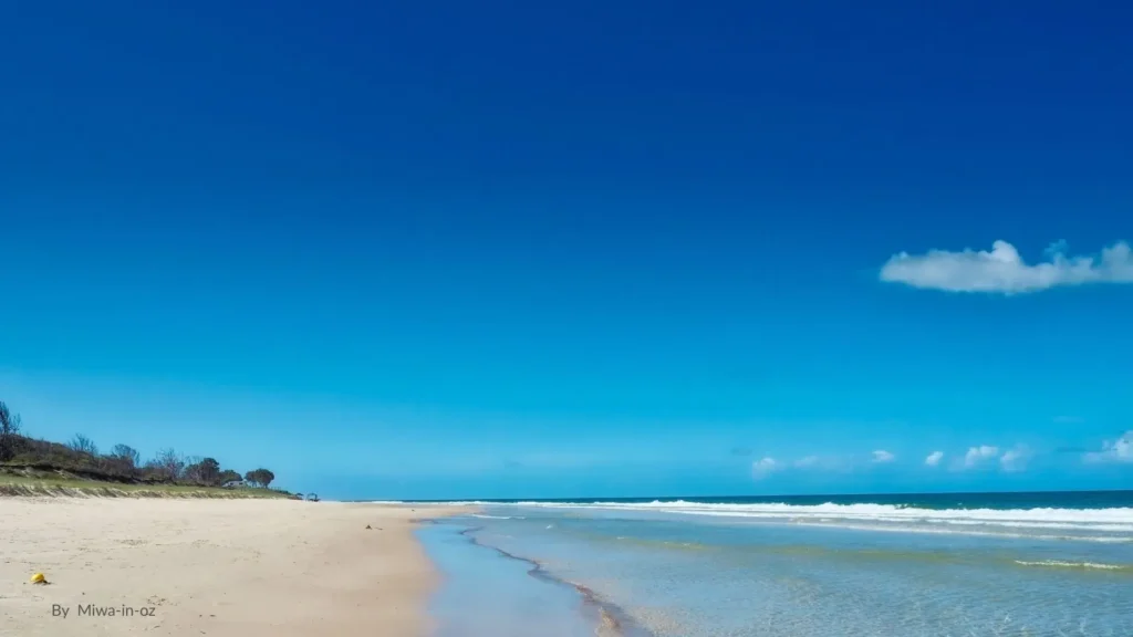 Woorim Beach, Bribie Island, Queensland, with golden sand and rolling surf under a clear blue sky