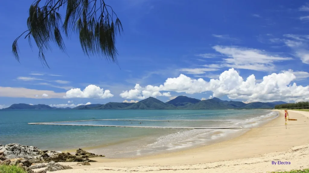 Yorkeys Knob Beach in Cairns, Queensland, with sandy foreshore, calm blue waters, and stinger nets under a tropical sky