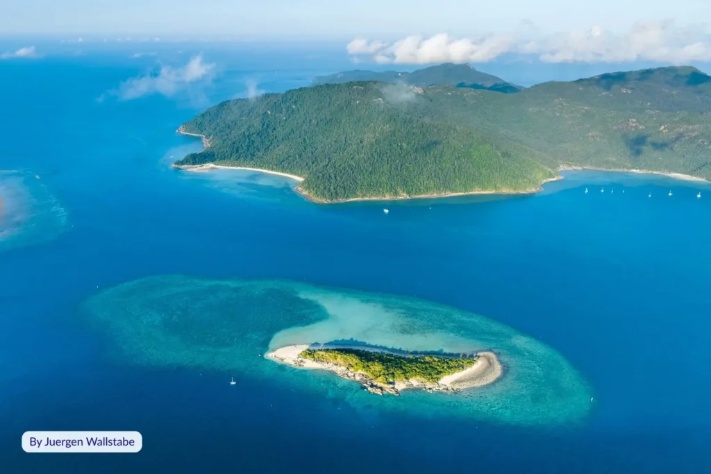 Aerial view of Black Island in the Whitsundays, Queensland – small sandy cay with turquoise water, coral reef, and lush island backdrop.