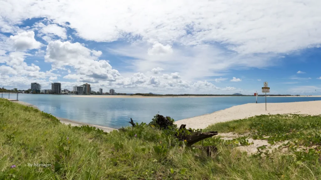 Panoramic view of Cotton Tree Beach with sandy foreshore, calm Maroochy River waters, and Maroochydore skyline in the distance, Sunshine Coast, Queensland.