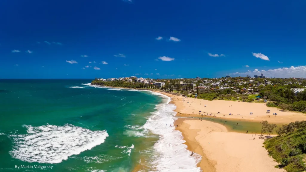 Aerial view of Dicky Beach with golden sand, rolling surf, and Caloundra township in the background, Sunshine Coast, Queensland.