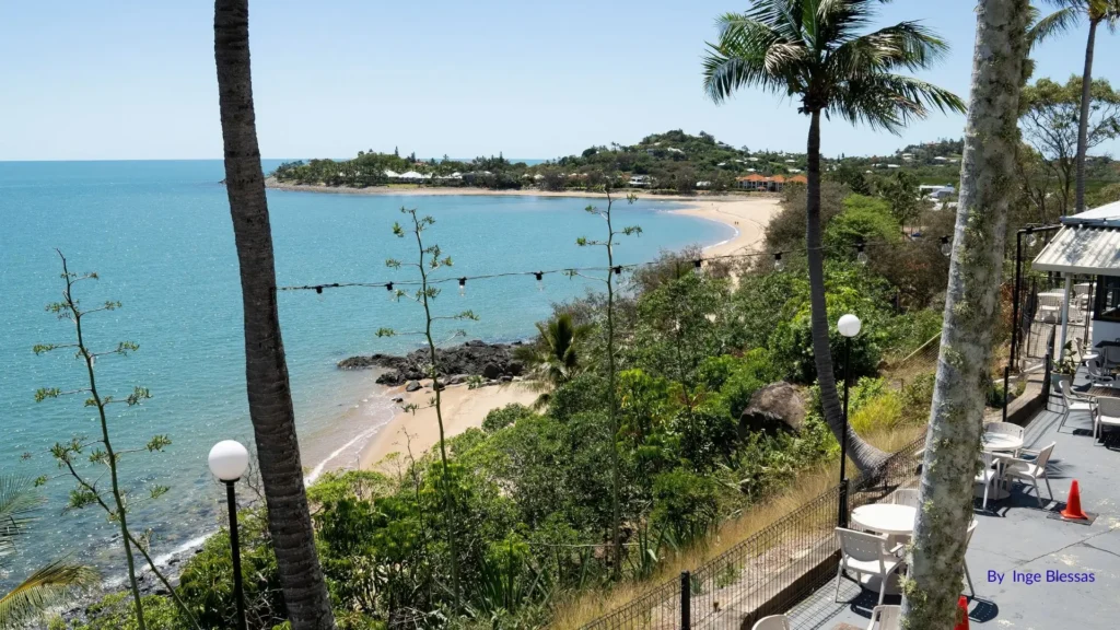 View of Eimeo Beach near Mackay, Queensland, with golden sand, calm blue waters, and palm trees framing the foreshore.