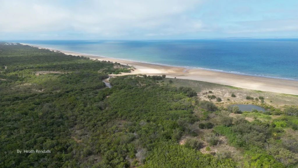 Aerial view of Farnborough Beach near Yeppoon, Queensland, showing its long sandy shoreline, turquoise waters, and lush green hinterland.