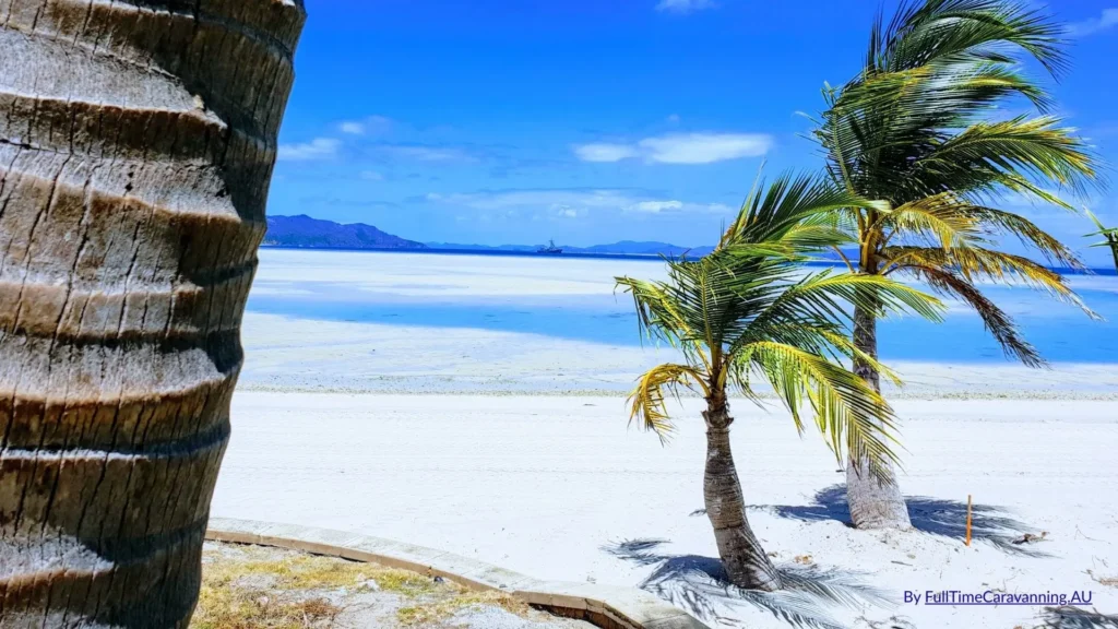 Palm trees and white sand on Hayman Island with turquoise waters and views across the Whitsundays, Queensland.