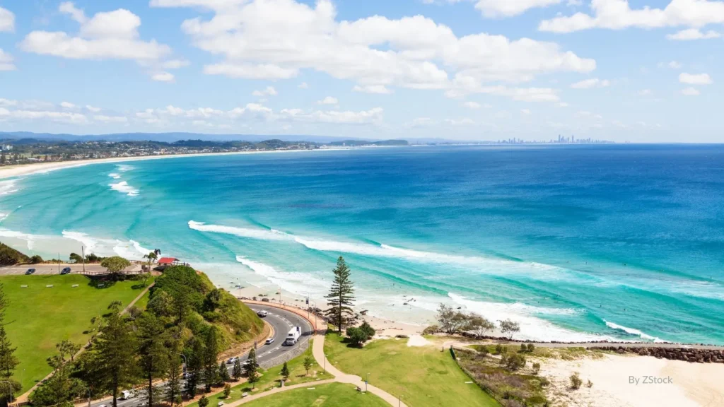 Aerial view of Kirra Beach with turquoise waves, golden sand, and Coolangatta headland in the distance, Gold Coast, Queensland.