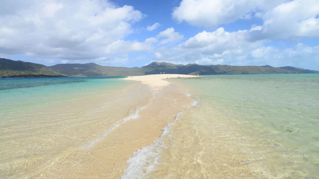 A sandy spit stretching into turquoise waters at Langford Island in the Whitsundays, Queensland, with clear skies and calm seas.