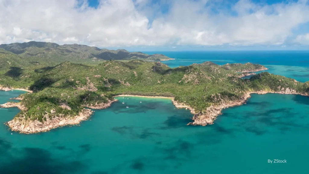 
Aerial view of Magnetic Island with turquoise waters, rocky headlands, and lush green hills off the coast of Townsville, Queensland.