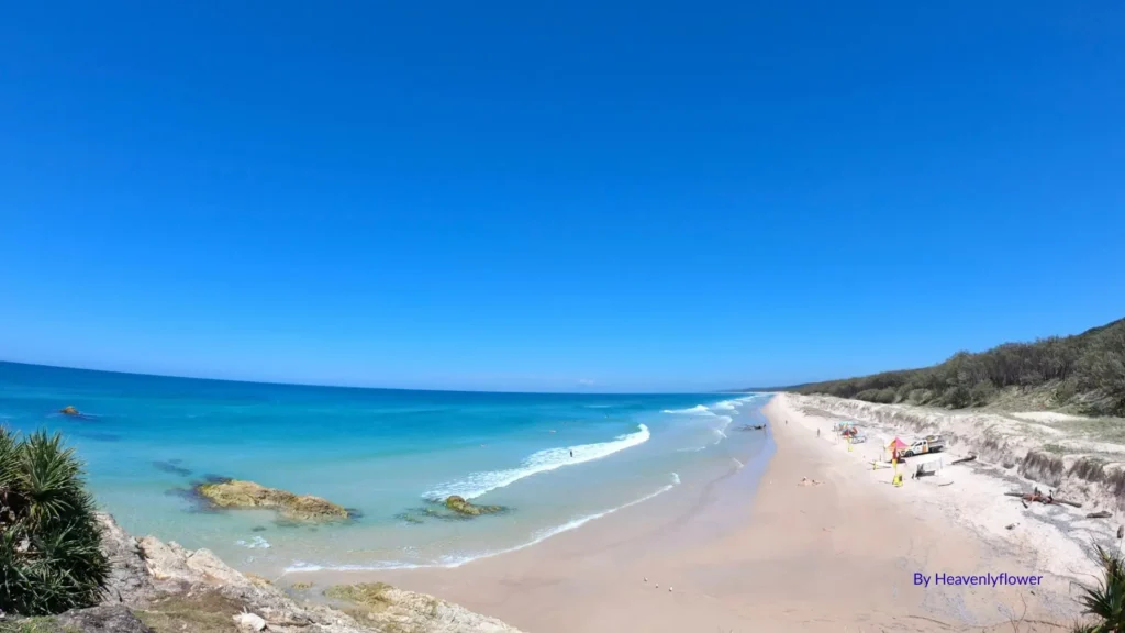 Main Beach on North Stradbroke Island with turquoise waves, golden sand, and long windswept shoreline stretching to the horizon, Point Lookout, Queensland.