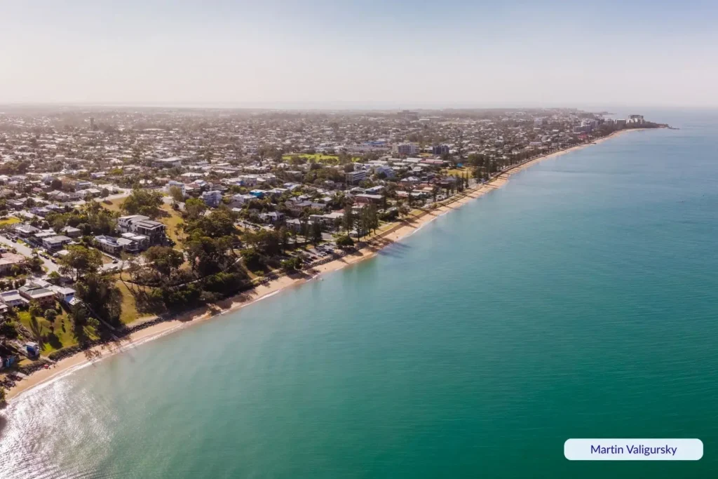 Aerial view of Margate Beach in Brisbane, Queensland, showing calm bay waters, sandy shoreline, and coastal houses along the waterfront.