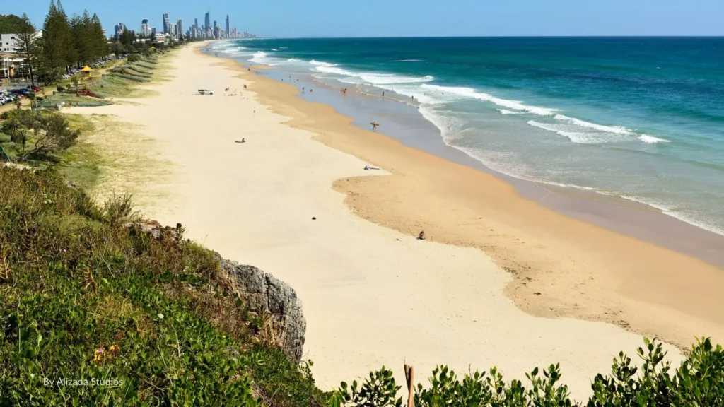 Scenic view of Miami Beach, Gold Coast, showing golden sandy shoreline, turquoise surf, and high-rises in the distance with beachfront parks in the foreground, Queensland, Australia.
