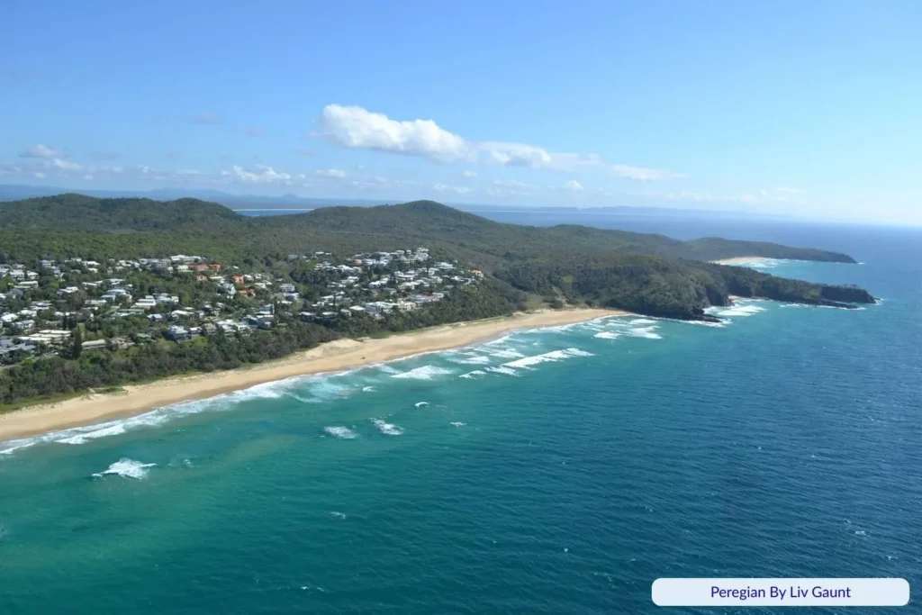 Aerial view of Peregian Beach, Sunshine Coast, Queensland with golden sand, turquoise waves, and residential houses along the headland.