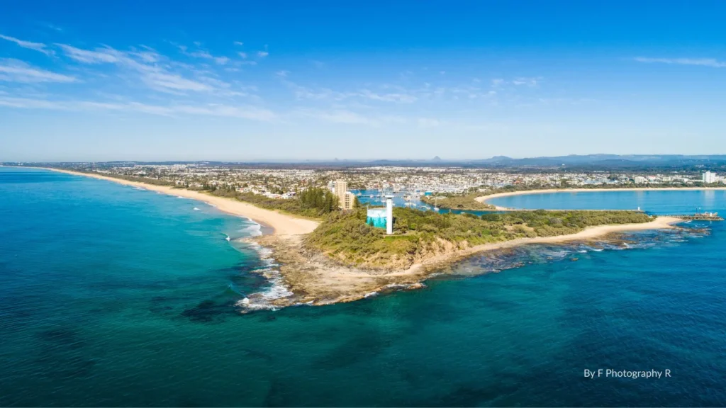 Aerial view of Point Cartwright Reserve with its white lighthouse, rocky headland, turquoise waters, and sandy beach, Sunshine Coast, Queensland.