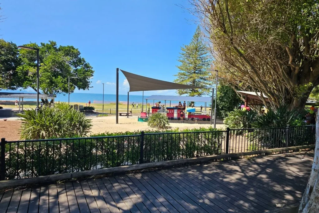 Scarborough Beach foreshore park with shaded playground, trees, and views of the sandy beach and Moreton Bay in the background, Redcliffe Peninsula, Brisbane, Queensland.