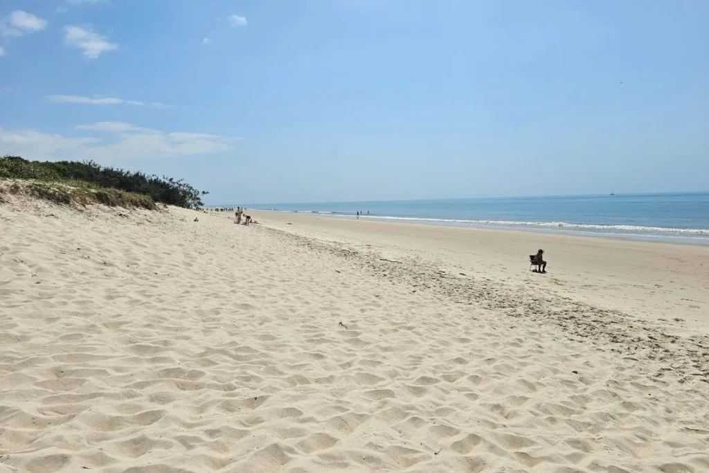 Expansive sandy foreshore at Woorim Beach on Bribie Island QLD, with golden sand stretching along the coastline and calm blue ocean under a clear sky.