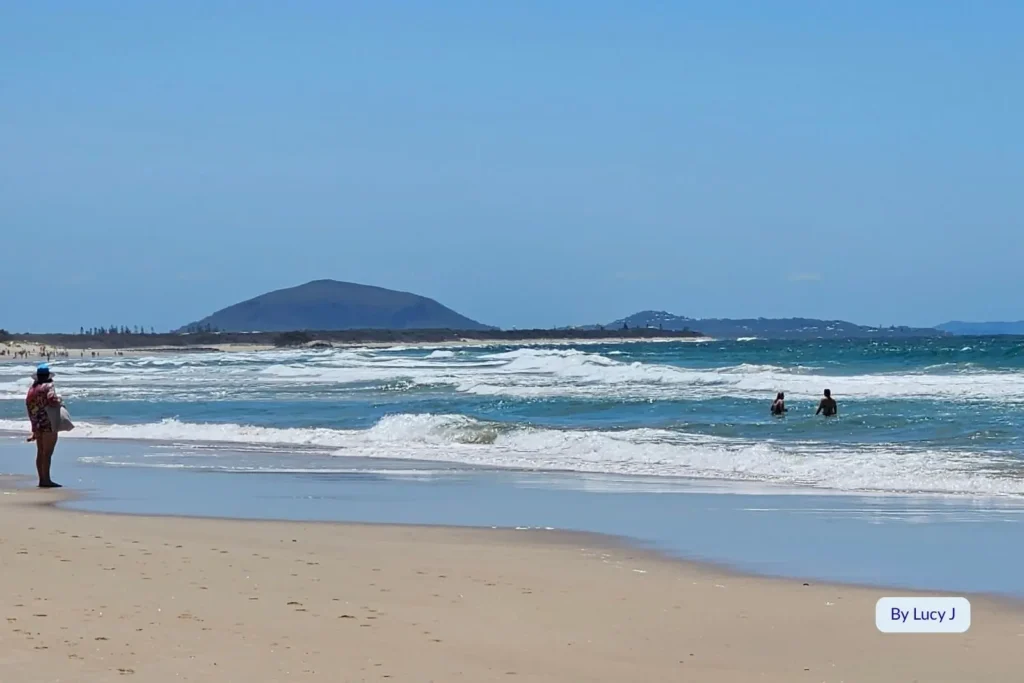 Swimmer enjoying sunny surf conditions at Alexandra Headland Beach with Mount Coolum visible in the distance, Sunshine Coast, Queensland.