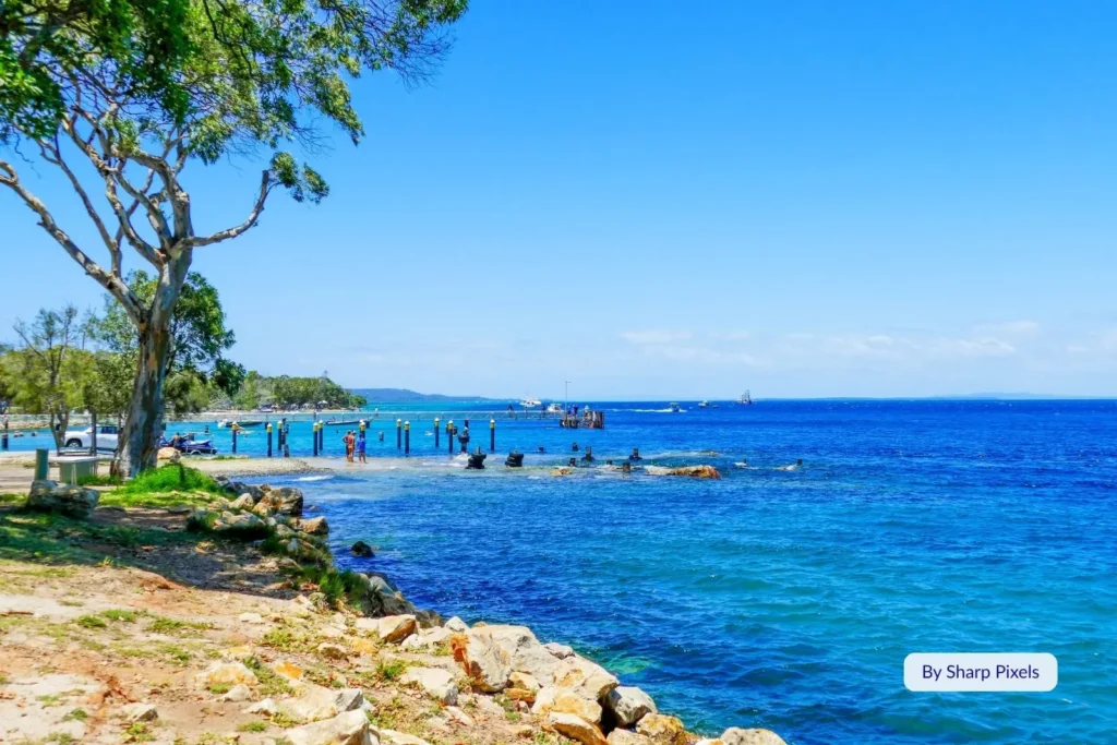 Rocky foreshore and jetty at Amity Point on North Stradbroke Island, Queensland, overlooking calm turquoise waters.