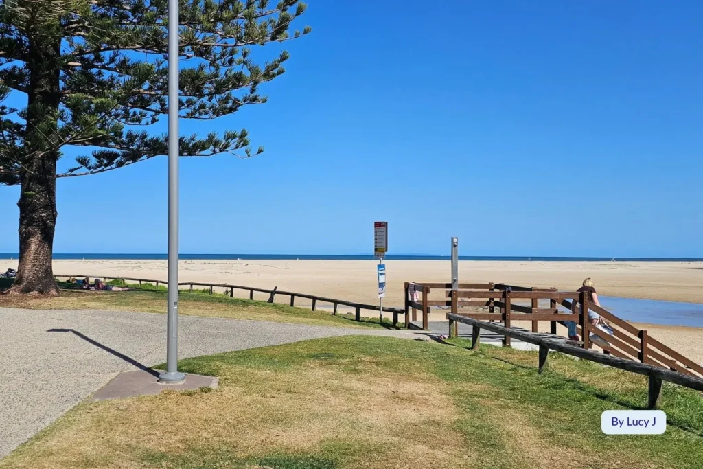 Wide sandy foreshore and boardwalk area at Bulcock Beach, Caloundra, under a clear blue sky, Sunshine Coast, Queensland.