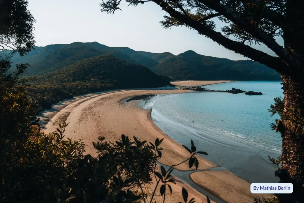Aerial view of Cape Hillsborough Beach, Queensland, showing curved golden sand, turquoise water, and lush forested headlands.