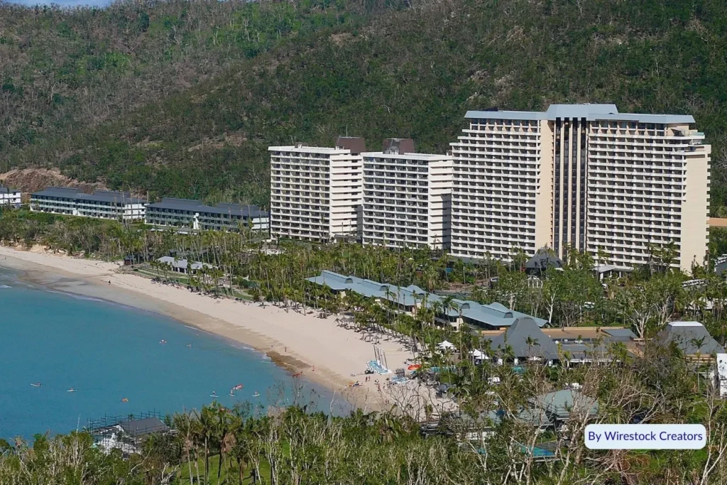 Aerial view of Catseye Beach and luxury Hamilton Island Resort nestled between lush green hills and blue ocean, Whitsundays, Queensland.
