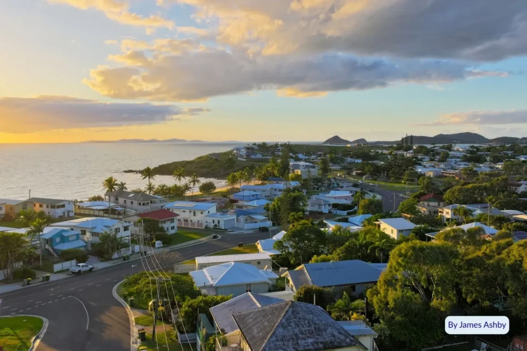 Aerial view of Cooee Bay and the seaside township near Yeppoon, Queensland, at sunset, showing coastline, homes, and scenic hills