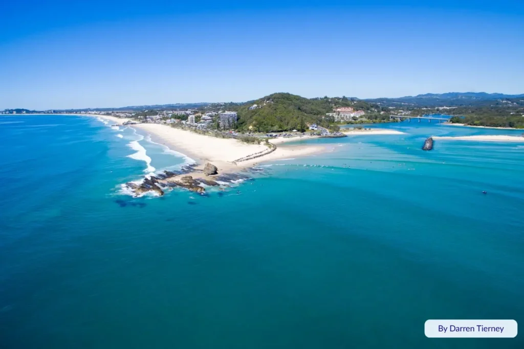 Aerial view of Currumbin Beach and Currumbin Alley showing clear blue water, sandbanks, and gentle waves along the southern Gold Coast, Queensland.