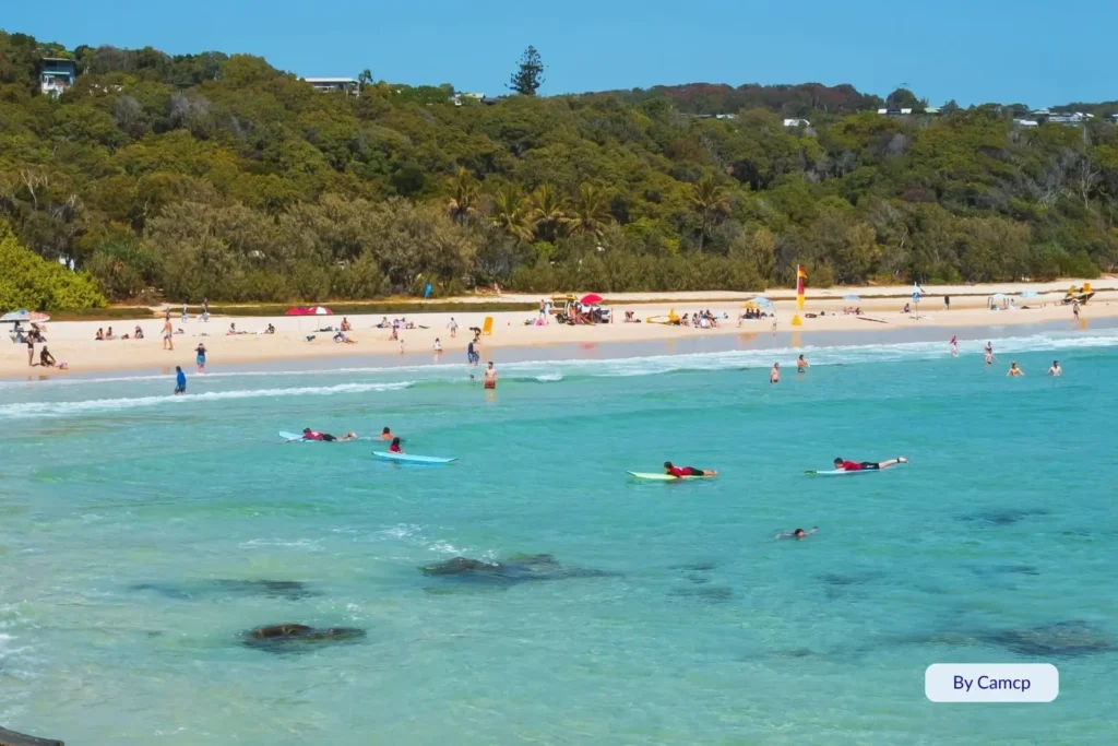 Swimmers and surfers in the clear aqua water at Cylinder Beach, Point Lookout, North Stradbroke Island, Queensland