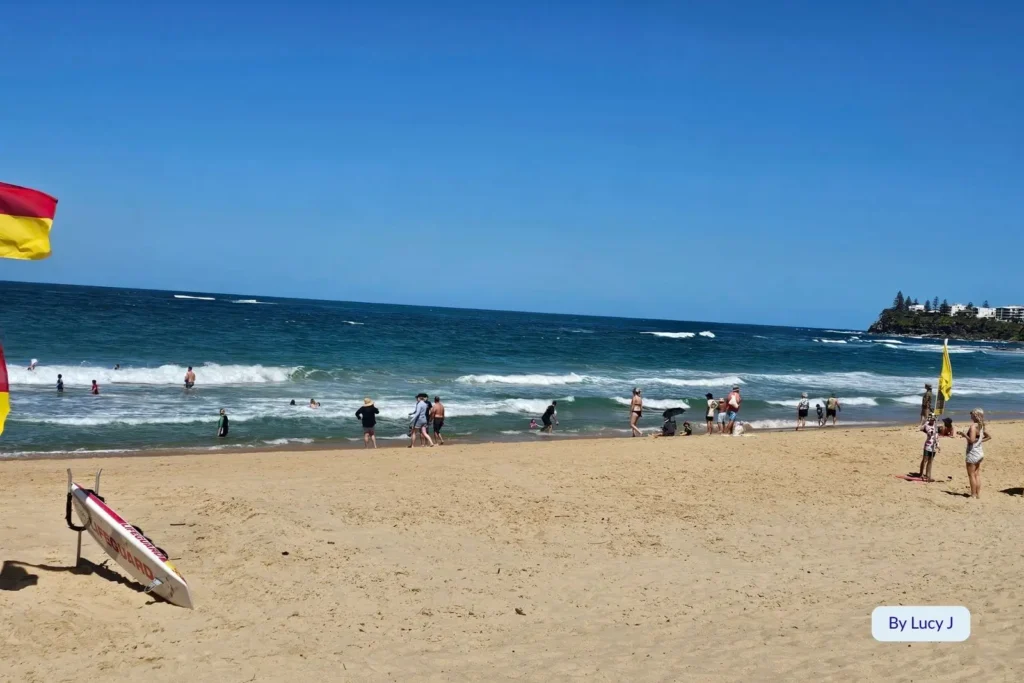 Lifeguard-patrolled Dicky Beach, Caloundra, on the Sunshine Coast, Queensland, with beachgoers swimming and relaxing under clear blue skies.