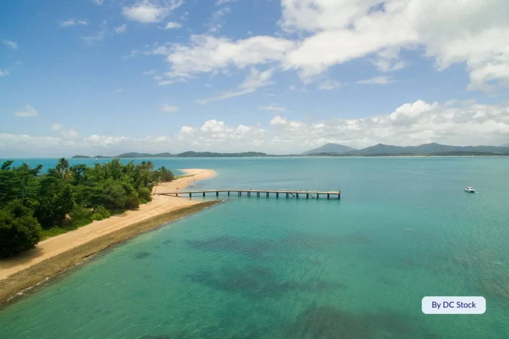Aerial view of Dunk Island jetty stretching into the Coral Sea with lush tropical rainforest and sandy beaches, Cassowary Coast, Queensland