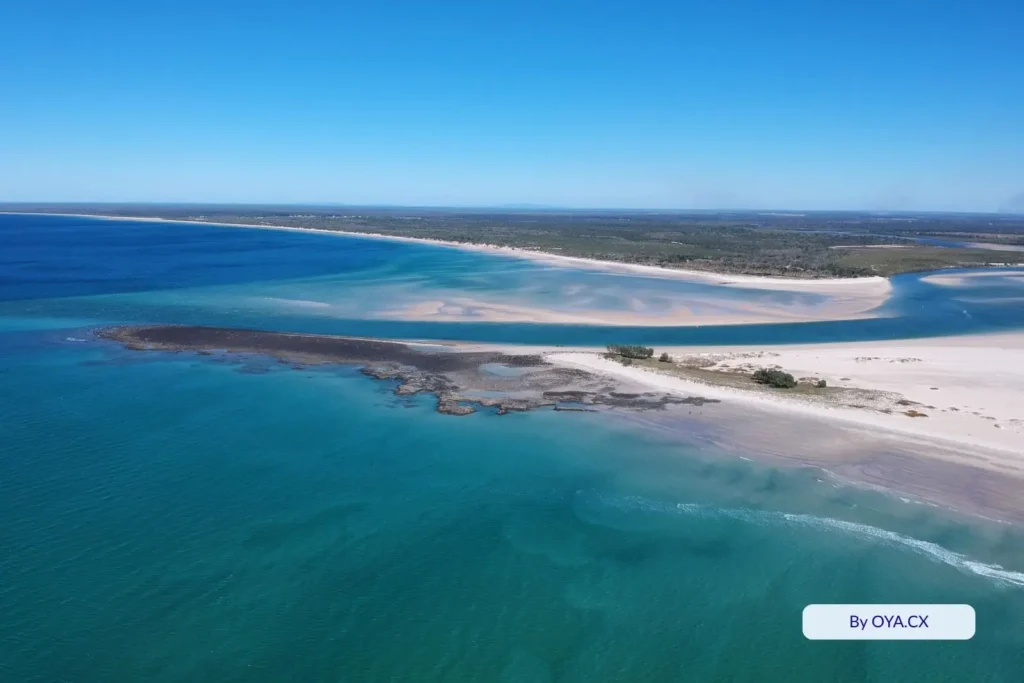 Wide aerial panorama of Elliott Heads, Queensland, capturing sandbars, the Elliott River inlet, and the striking contrast of deep blue and aqua coastal waters
