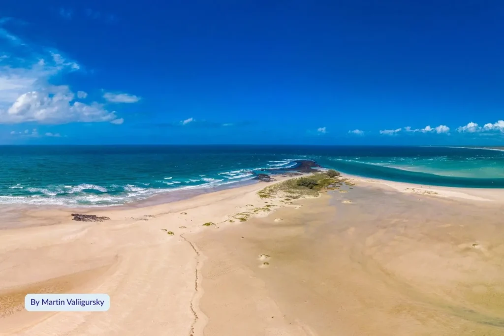 Aerial photo of Elliott Heads Beach, Bundaberg Region, Queensland, with golden sand and turquoise waves meeting at the river mouth.