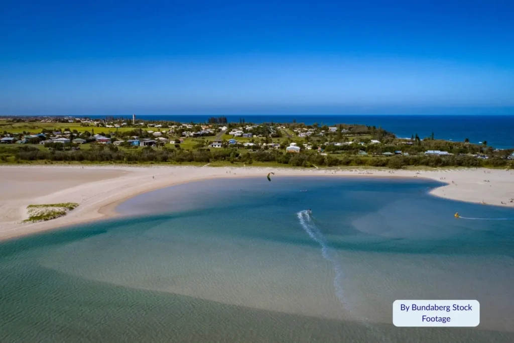 Scenic aerial view of Elliott Heads estuary in Bundaberg, Queensland, showing calm blue waters, white sand flats, and coastal town surroundings