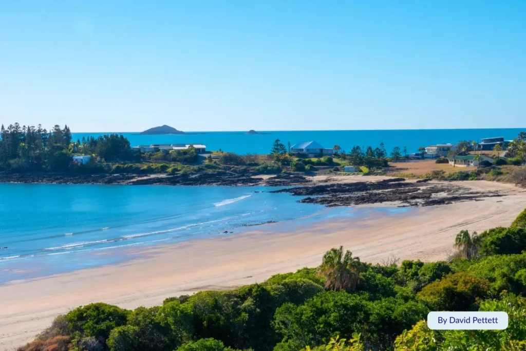 Scenic view of Emu Park Main Beach and township on the Capricorn Coast, Queensland, showing calm blue water and coastal headland