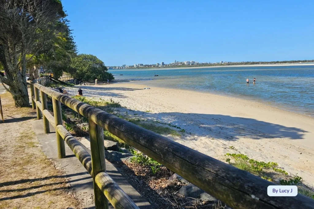 Wooden foreshore railing overlooking calm blue water and sandy shoreline at Golden Beach, Caloundra, Sunshine Coast, Queensland.
