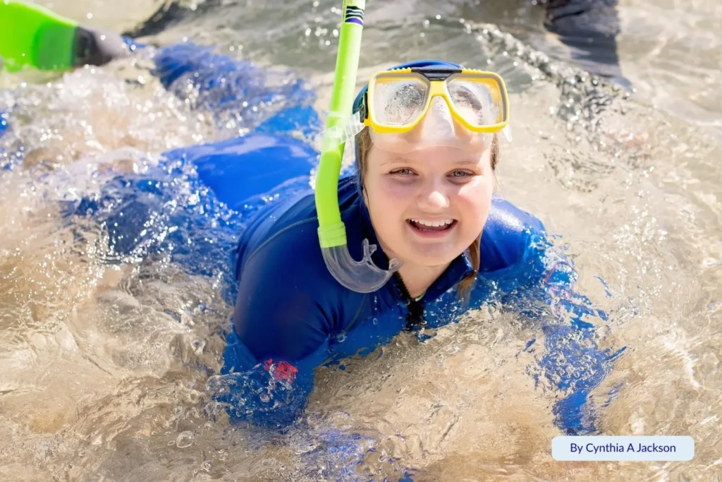 Child in snorkel gear enjoying clear shallow waters at Green Island, Great Barrier Reef, Queensland, Australia.