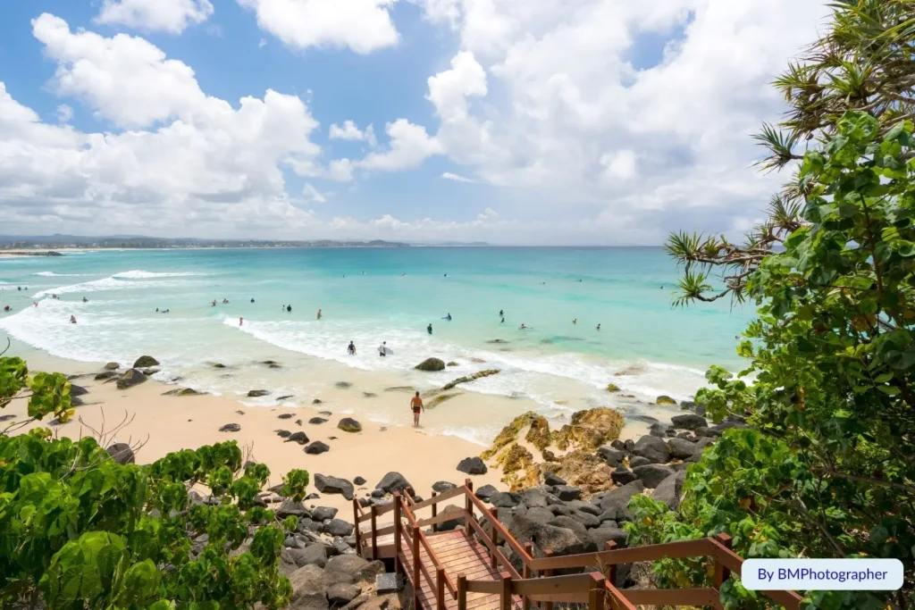 Scenic view of Greenmount Beach from the lookout stairs with swimmers enjoying turquoise water and soft white sand, Coolangatta, Gold Coast, Queensland.