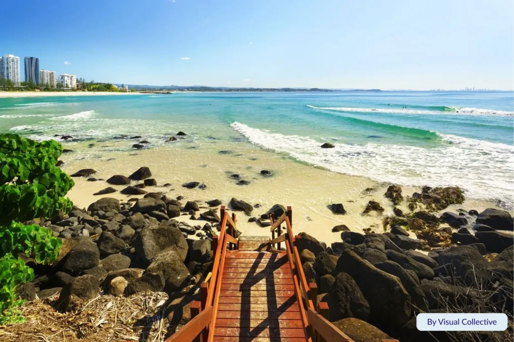View from the boardwalk overlooking Greenmount Beach with gentle waves, golden sand, and clear turquoise water, Coolangatta, Gold Coast, Queensland.