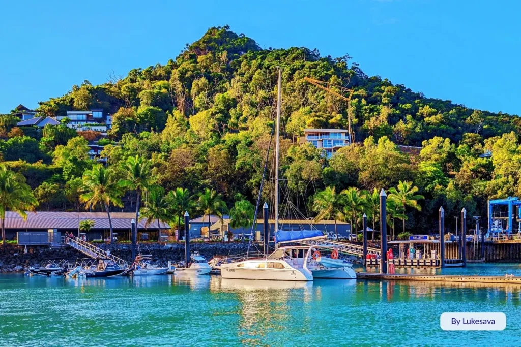 Sailboat docked at the Hamilton Island Marina surrounded by tropical greenery and hillside resorts, Whitsundays, Queensland.