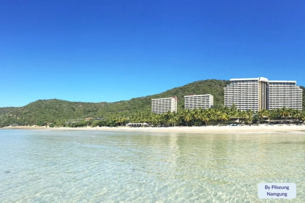 Clear shallow water and beachfront resort buildings along Catseye Beach on Hamilton Island, Great Barrier Reef, Queensland, Australia.