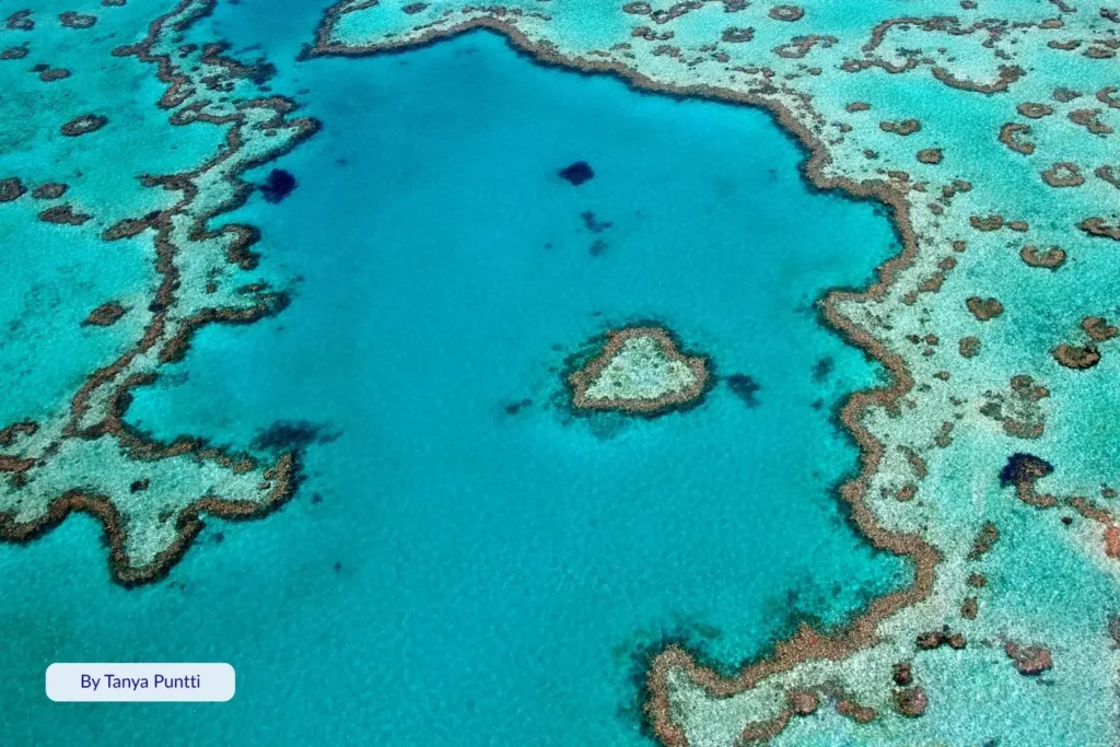 Scenic aerial view of Heart Reef, Whitsundays, Queensland, showing the heart-shaped coral lagoon within the Great Barrier Reef’s vivid blue waters.