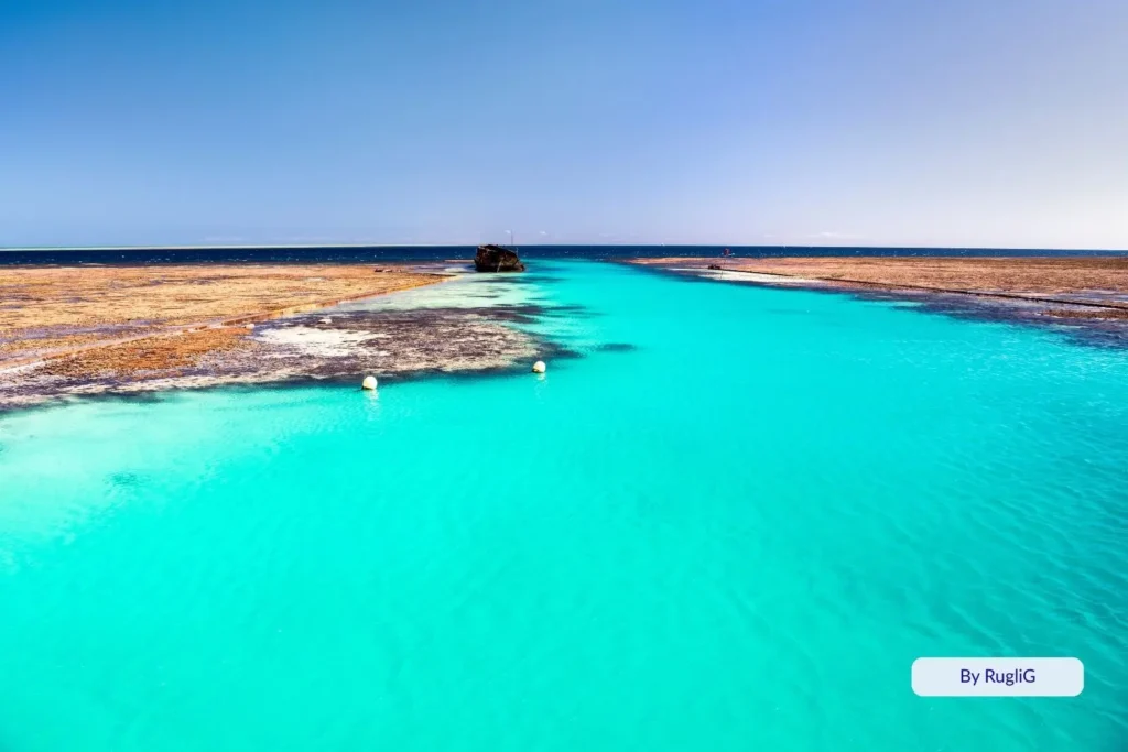 Bright turquoise lagoon and coral reef flats at Heron Island, southern Great Barrier Reef, Queensland, with clear shallow waters under sunny skies.