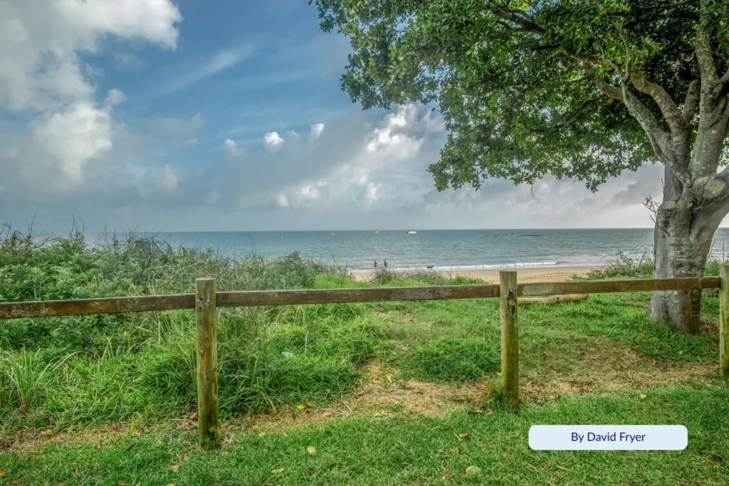 Peaceful grassy park area with ocean views and wooden fence along Hervey Bay Esplanade, Queensland.