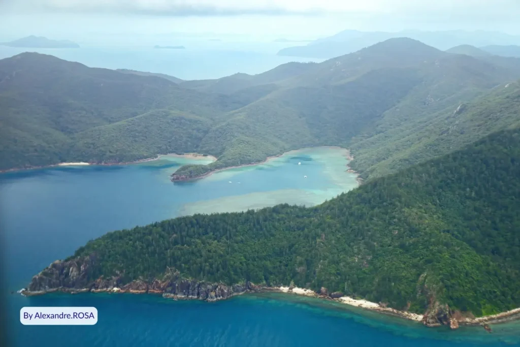 Aerial view of Hook Island in the Whitsundays showing forested mountains, secluded bays, and turquoise Coral Sea waters, Queensland, Australia.