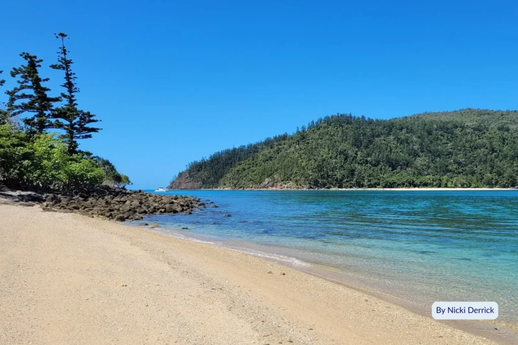 Sandy beach with calm blue waters and lush green headlands on Hook Island, Whitsundays, Great Barrier Reef, Queensland.
