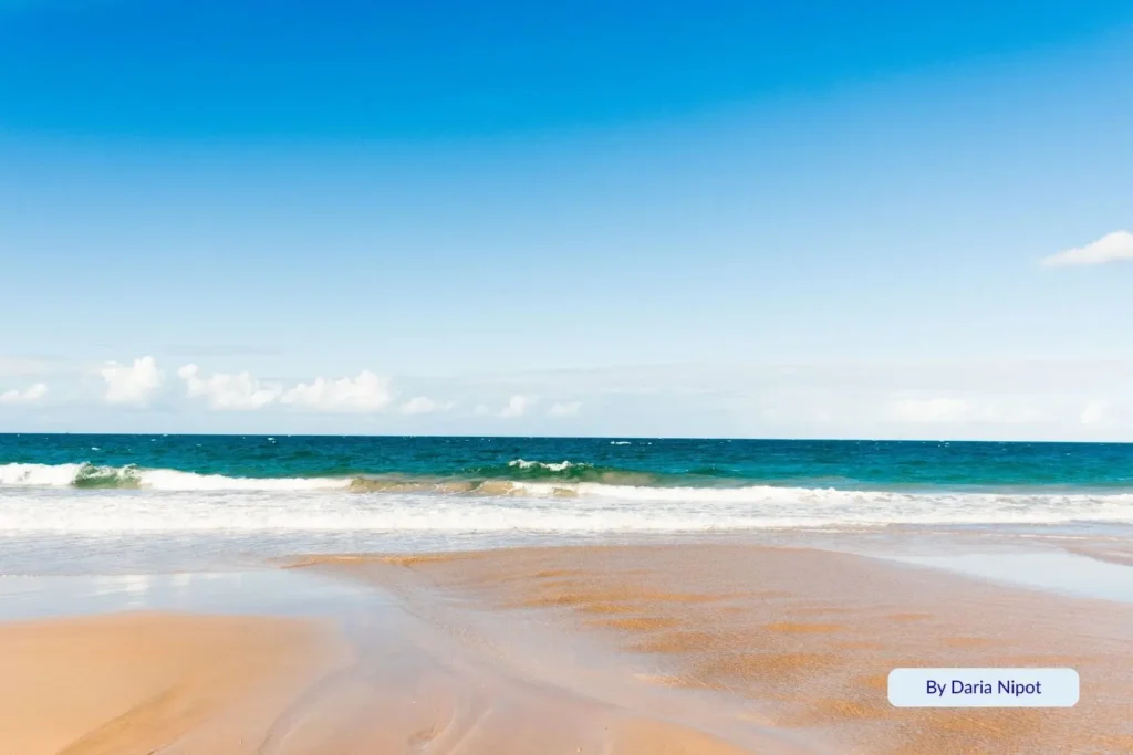 Golden sand and gentle turquoise waves at Kellys Beach in Bargara, Bundaberg, Queensland, under a clear blue sky