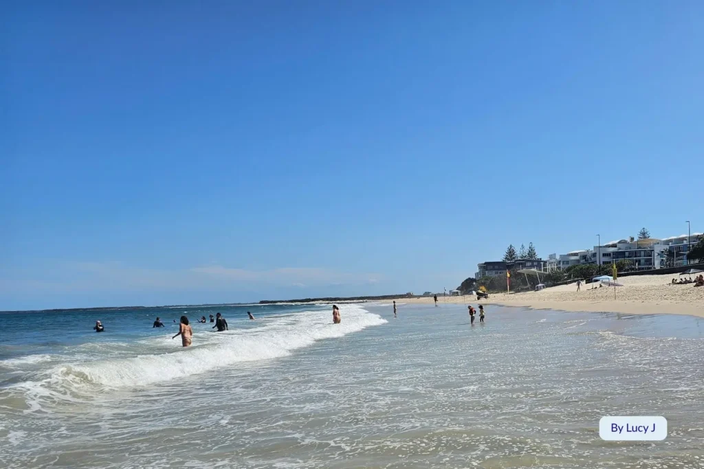 Swimmers cooling off in the rolling waves at Kings Beach, Caloundra, under clear blue skies on the Sunshine Coast, Queensland.