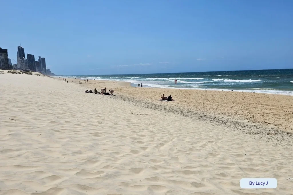 Wide sandy shoreline of Kurrawa Beach stretching towards Surfers Paradise skyline under a clear blue sky, Gold Coast, Queensland.